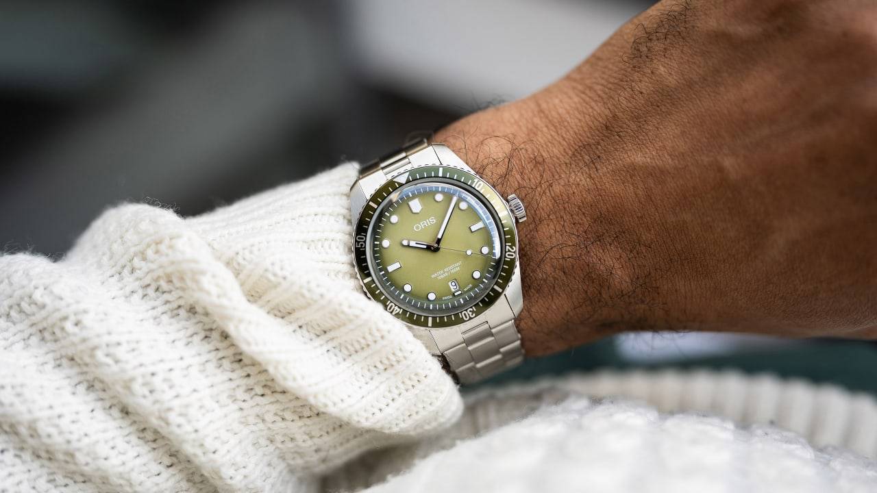 Oris Divers Sixty-Five Date Automatic Herenhorloge 40mm met olijfgroene wijzerplaat en roestvrijstalen band, gedragen om pols. Swiss Made duikhorloge voor heren.