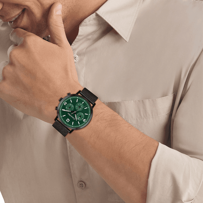 Calvin Klein CK25200440 Gauge herenhorloge 44mm met groene wijzerplaat en zwarte mesh band, gedragen door man in beige overhemd. Stijlvol quartz horloge voor heren.